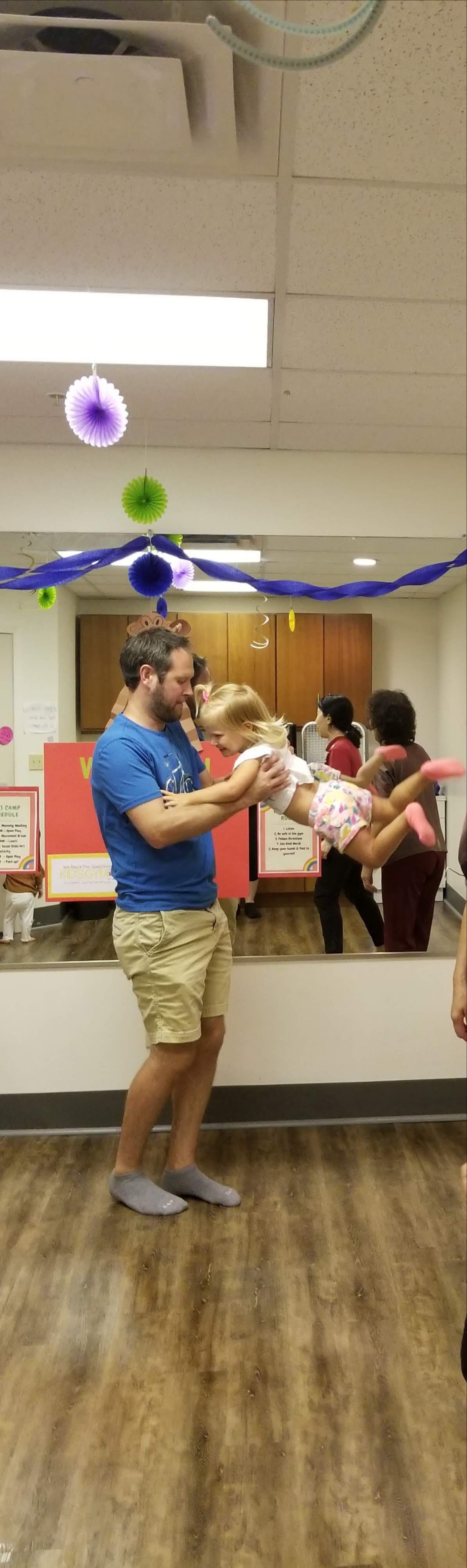 A dad dancing and lifting his daughter during a Zumbini class