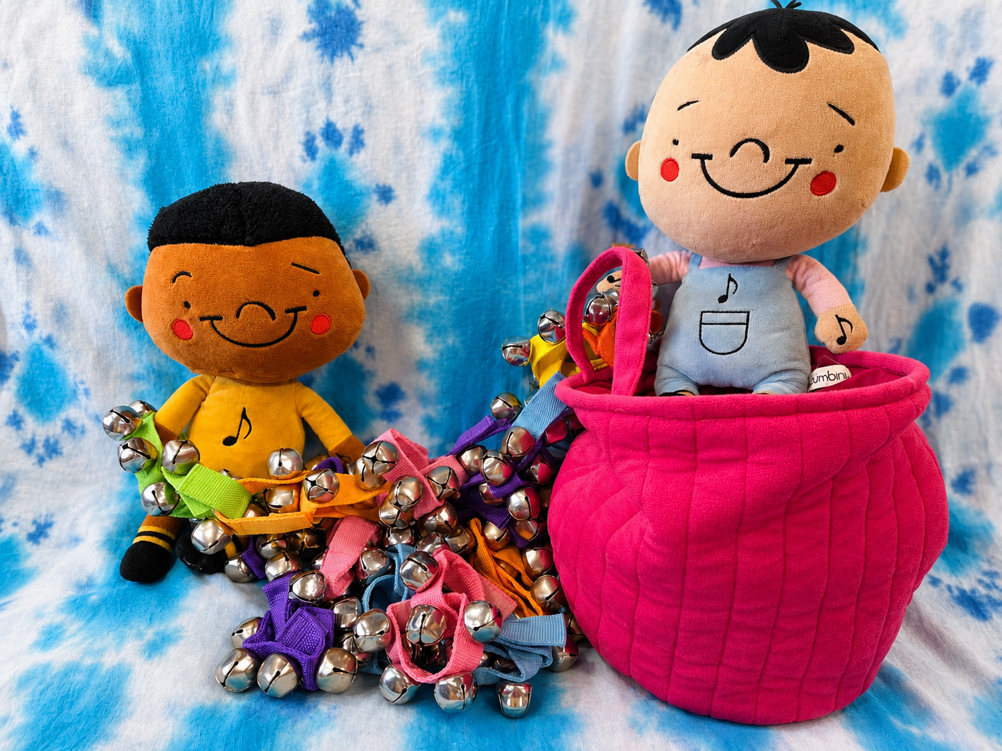 Colorful jingle bell wristbands piled with smiling Zumbini character dolls