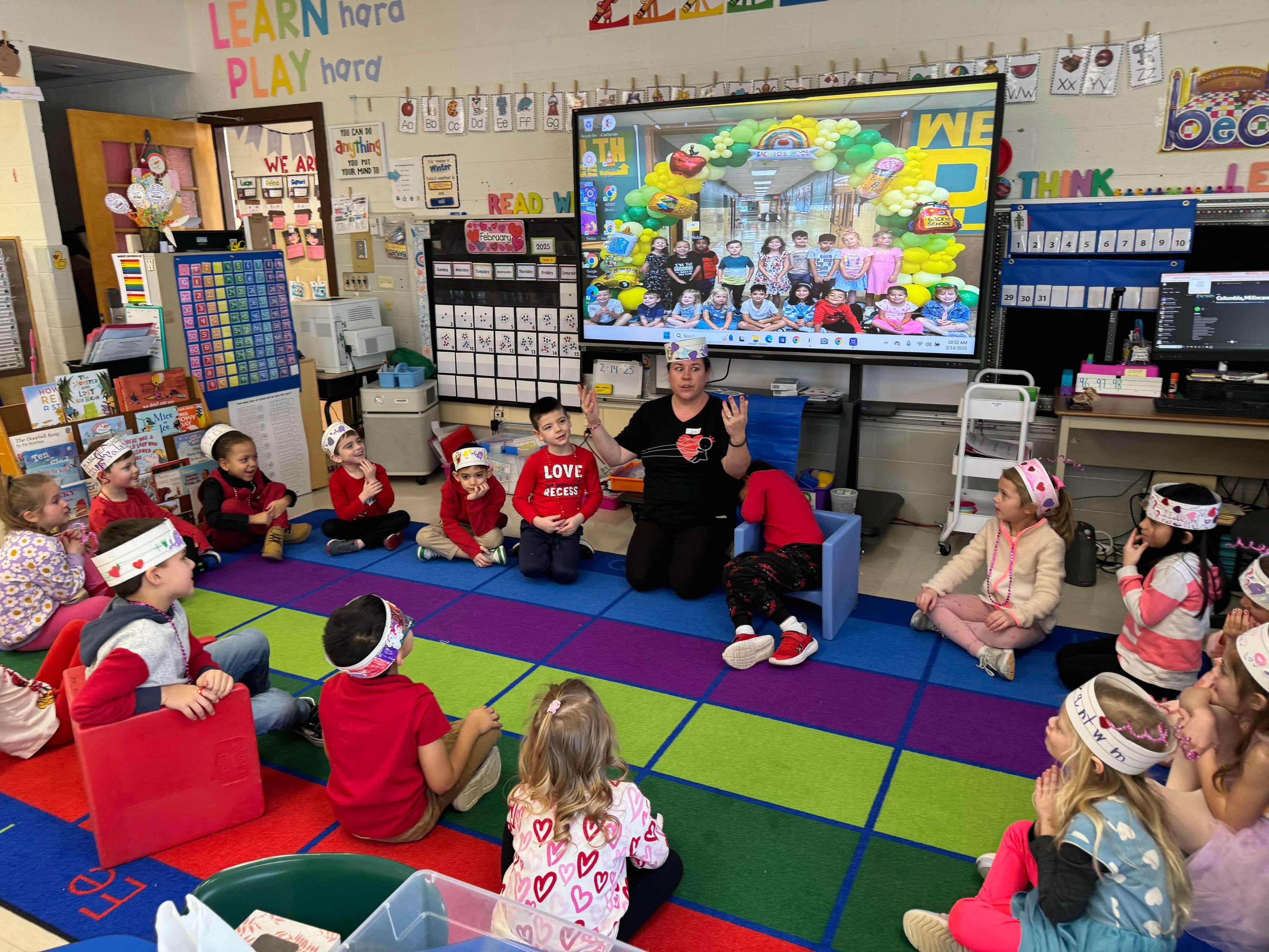 Miss Bri leading a Zumbini class with children sitting on a colorful rug